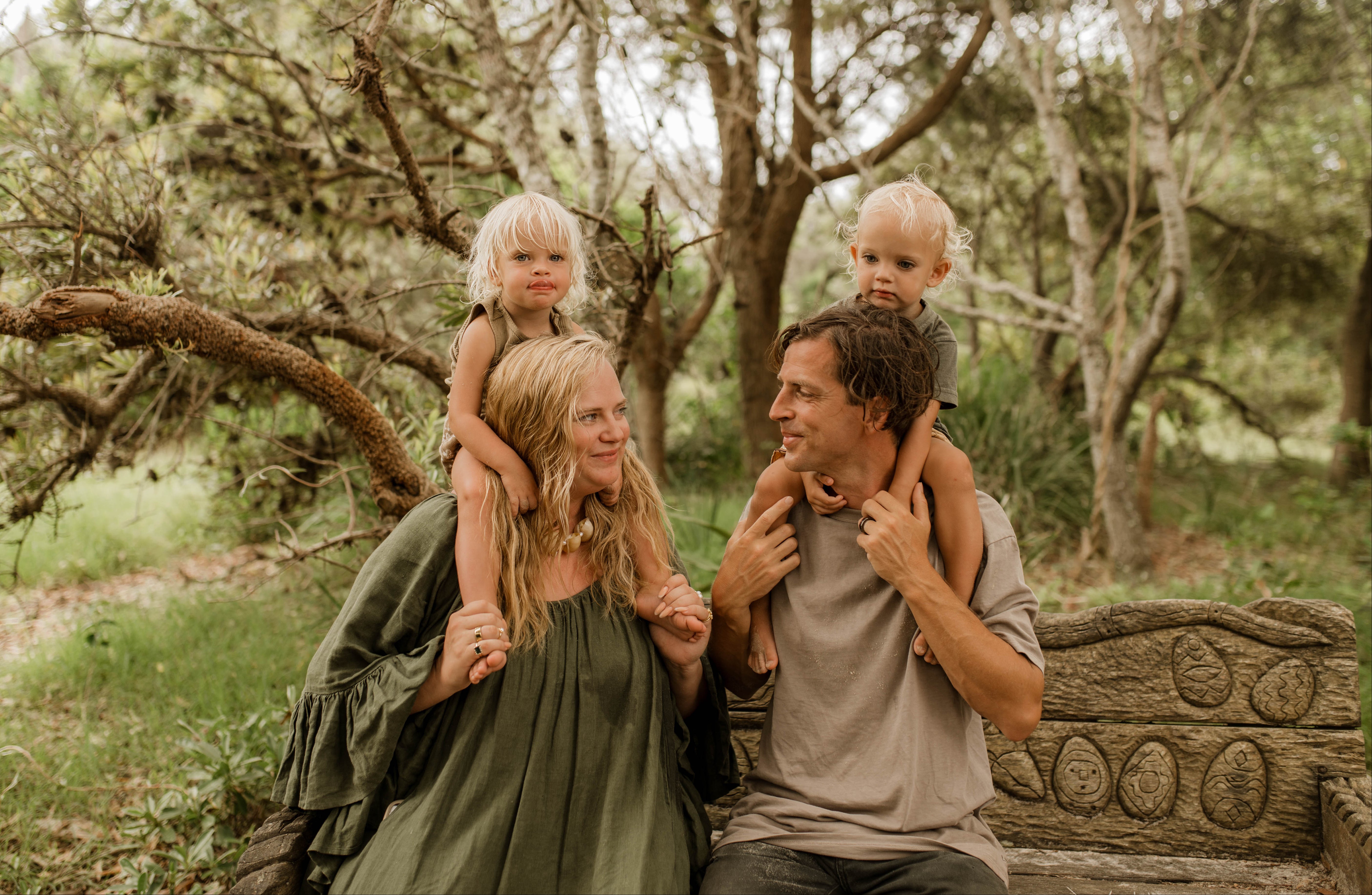 Family of four sitting on a stone bench in a forest setting