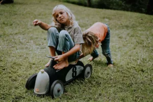 Two reconnected children playing together on a tin race car