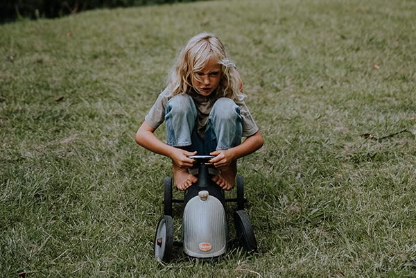 A strong-willed child riding a trike with a determined facial expression
