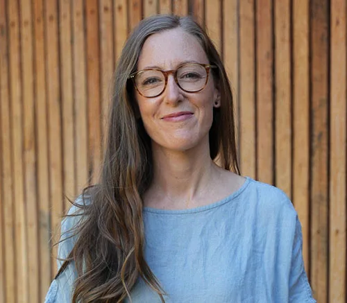 Naturopath Sarah Mann, standing in front of a wood panel wall and smiling